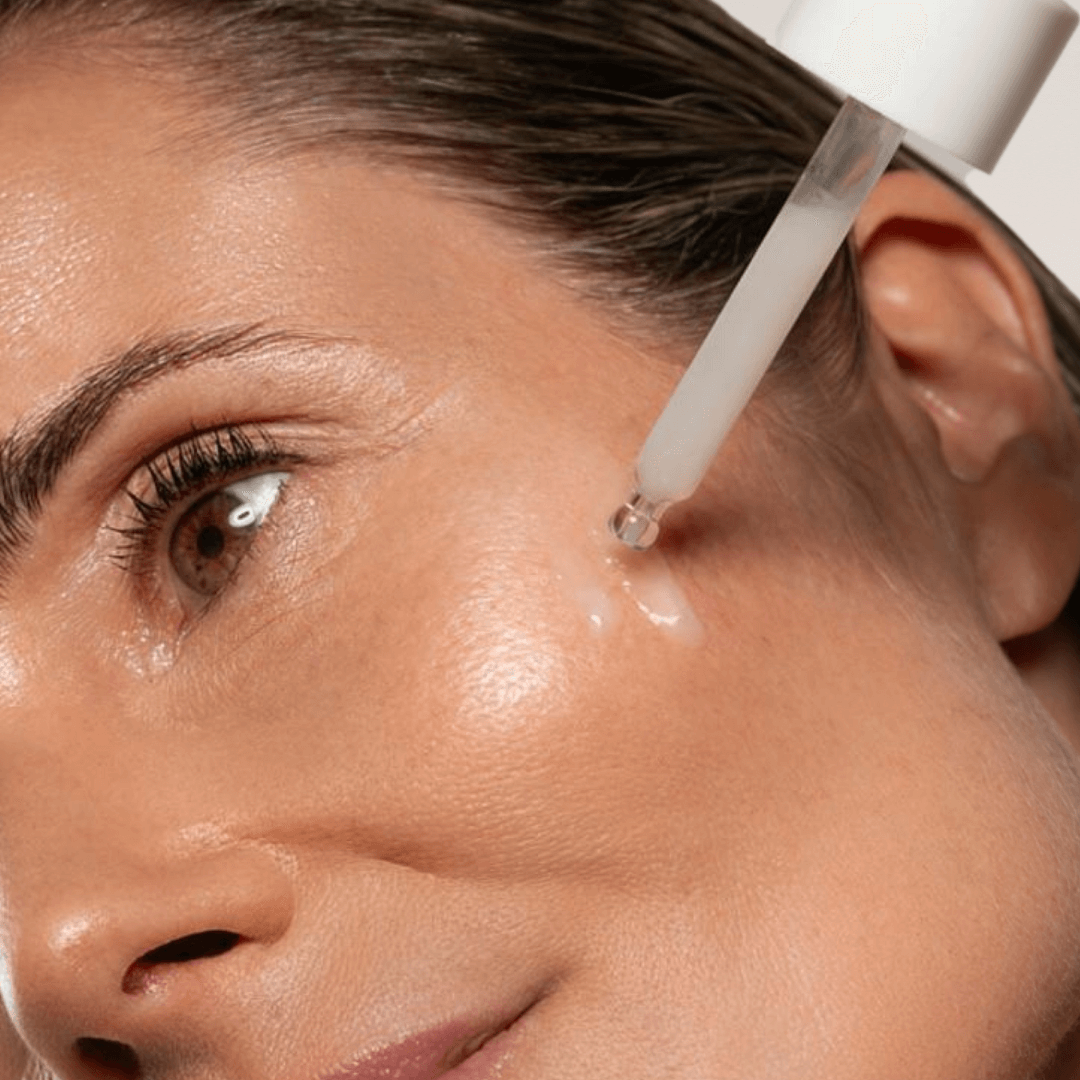 women applying skincare liquid on face