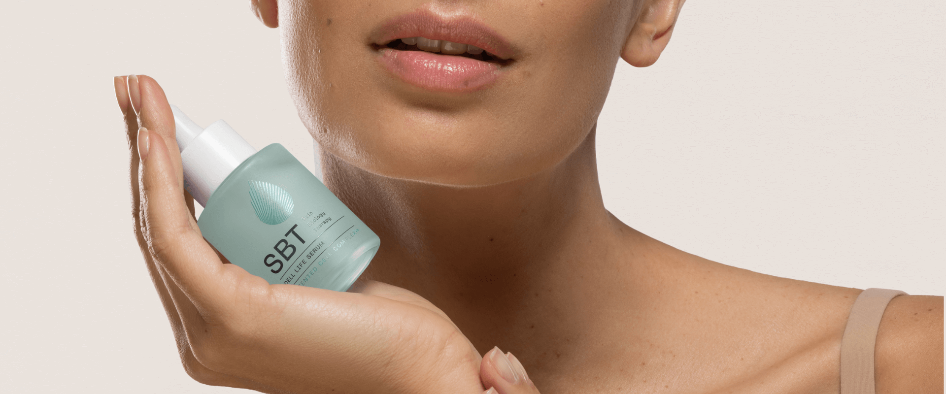 women holding SBT cell life serum in hand with beige background