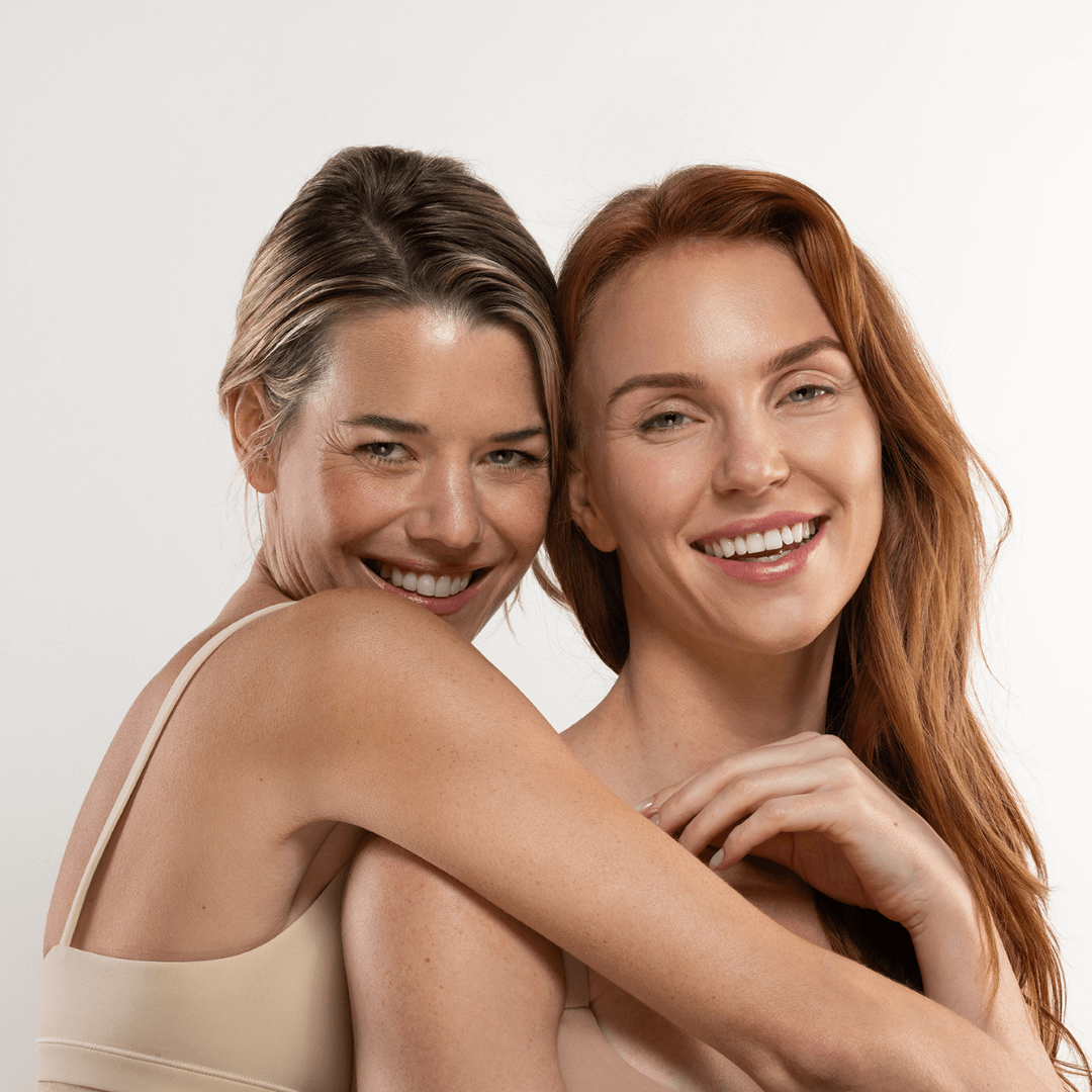 two women posing with beige background