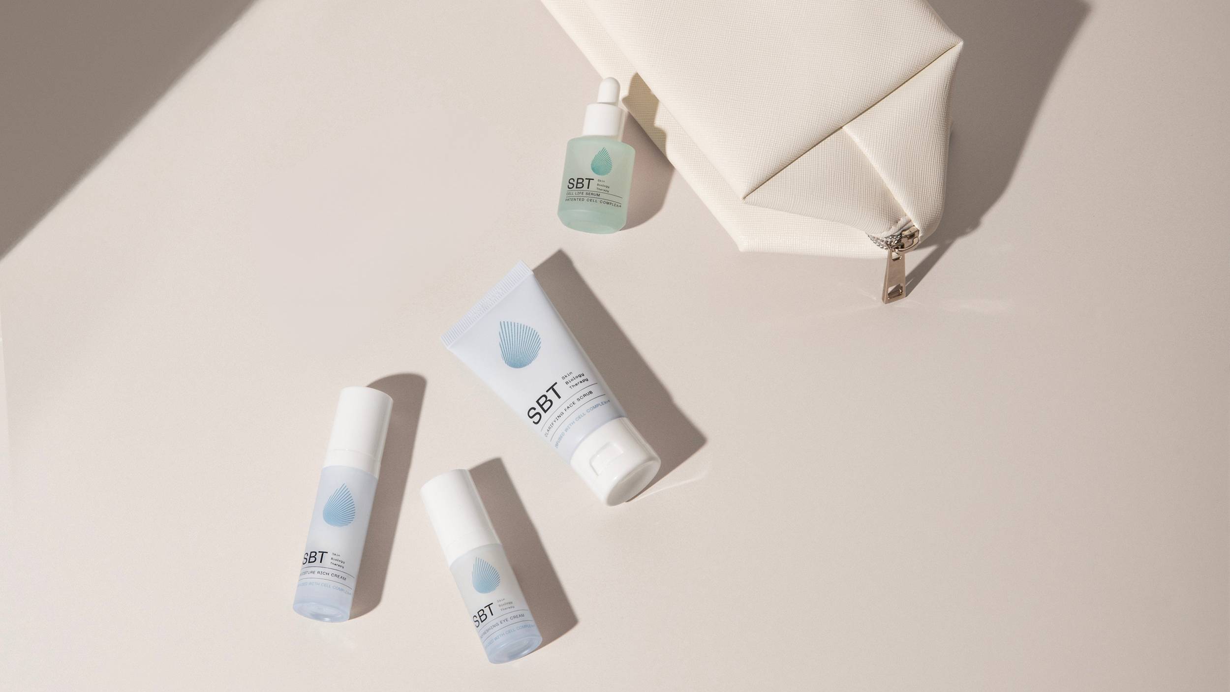 Set of skincare products with a cream-colored pouch on a beige background