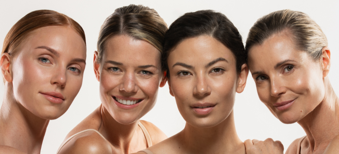 Four women with different skin tones and expressions on a beige background